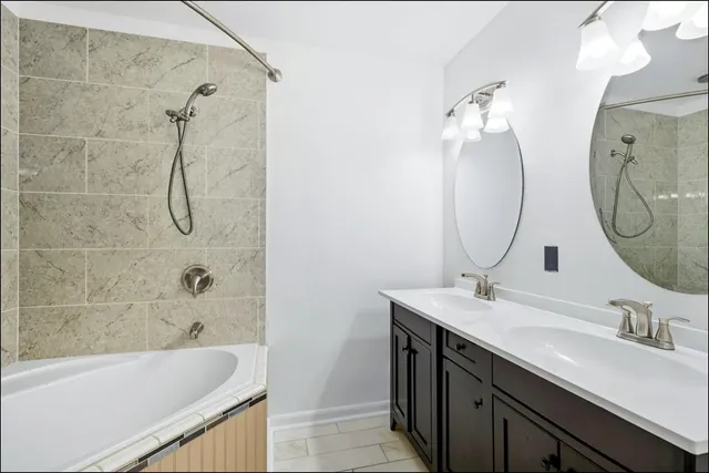 a bathroom with a double vanity sink mirror and bathtub