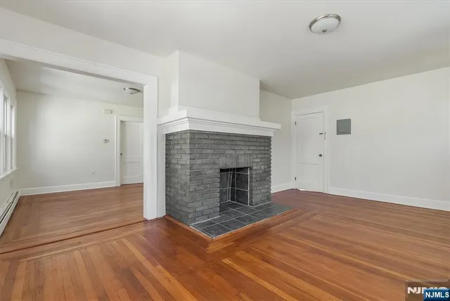an empty room with wooden floor and fireplace
