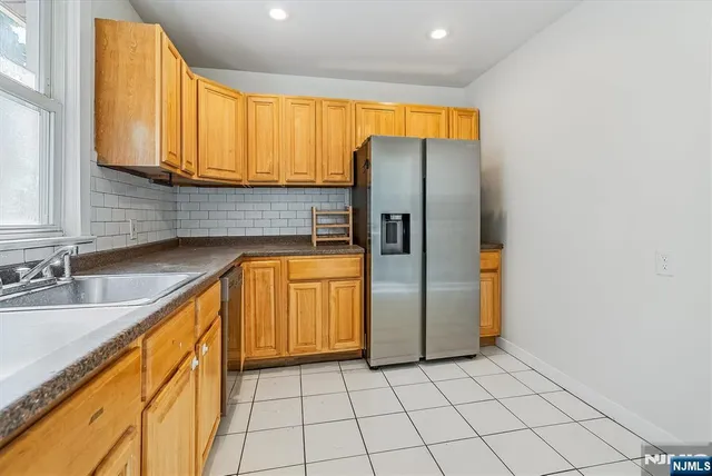 a kitchen with stainless steel appliances granite countertop a refrigerator a sink and dishwasher with wooden cabinets
