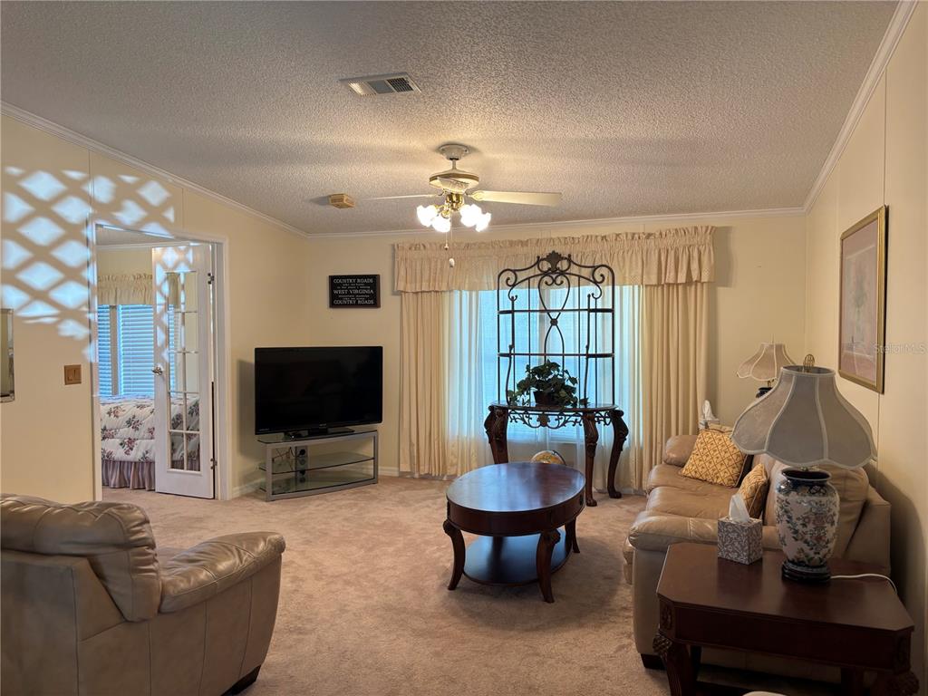 1759 Southwest 35th Circle Okeechobee, FL 34974 - Photo 7 of 29 a living room with furniture a ceiling fan and a flat screen tv
