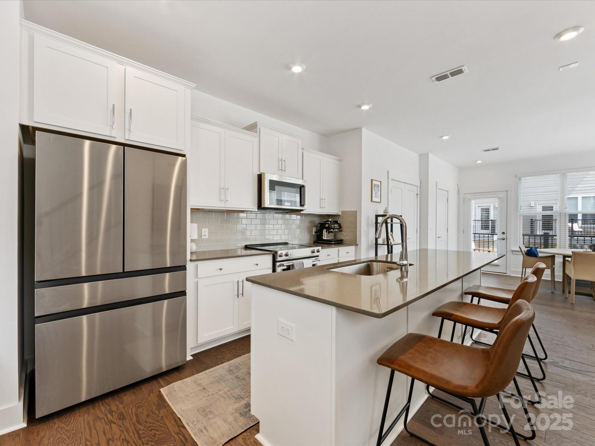 4027 Capital Ridge, Unit 10 Charlotte, NC 28205 - Photo 6 of 34 a kitchen with stainless steel appliances granite countertop a refrigerator a stove a sink a dining table and chairs with wooden floor