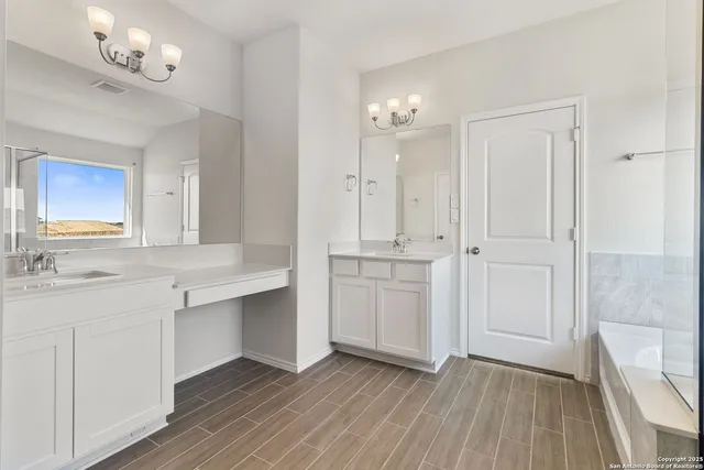 a bathroom with a sink double vanity granite tub and a mirror