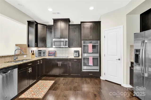 a large kitchen with stainless steel appliances granite countertop a refrigerator and a sink