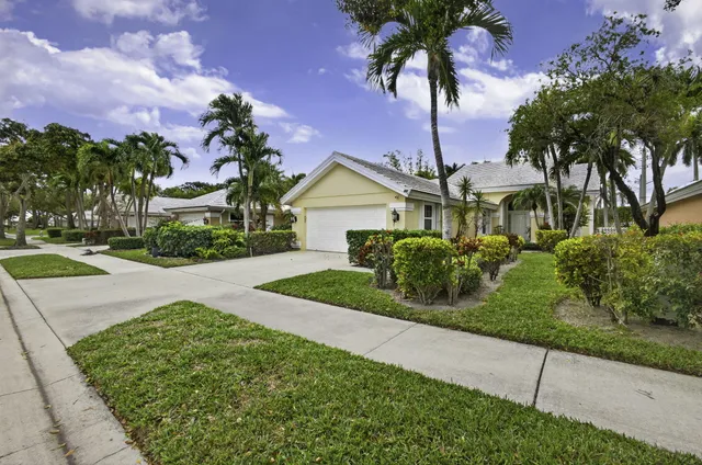 a front view of a house with a garden and tree