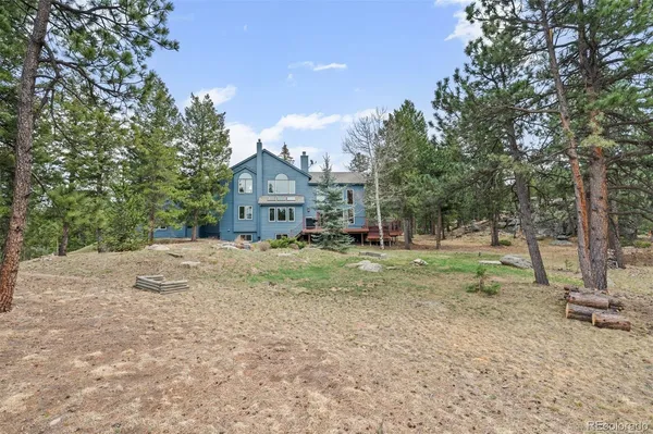 a backyard of a house with large trees and wooden fence