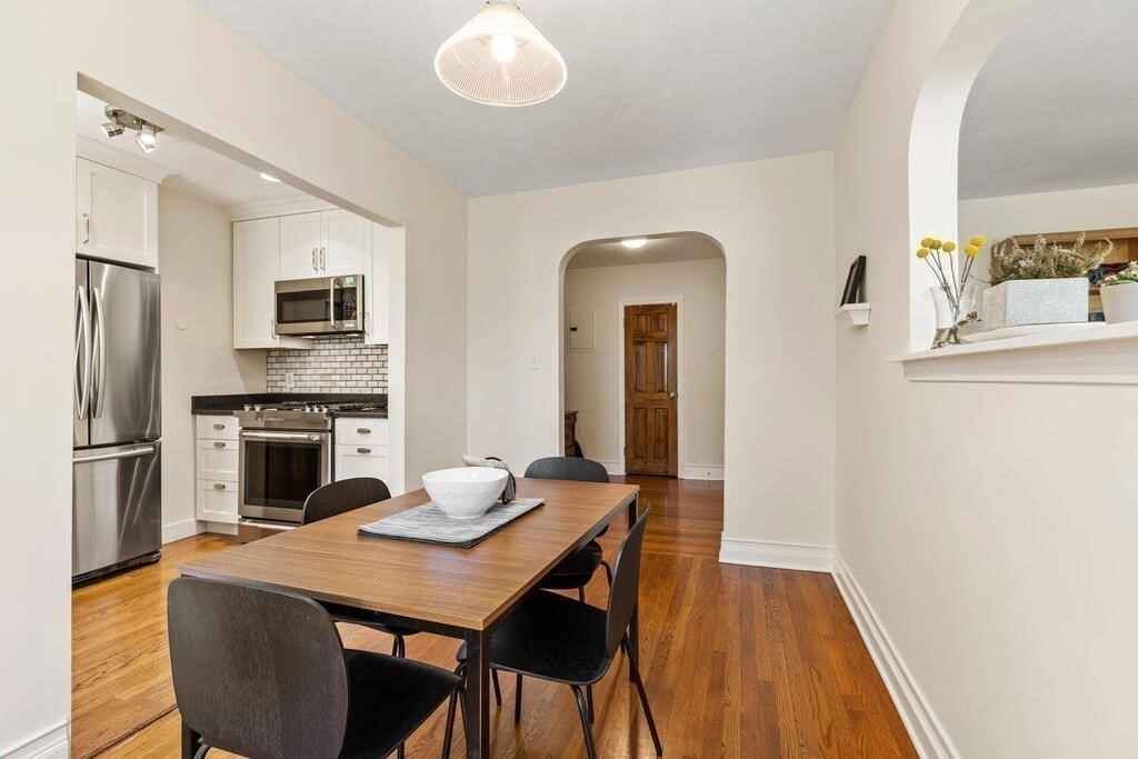 395 Broadway, Unit R5E Cambridge, MA 02139 - Photo 10 of 27 a kitchen with a table chairs refrigerator and microwave