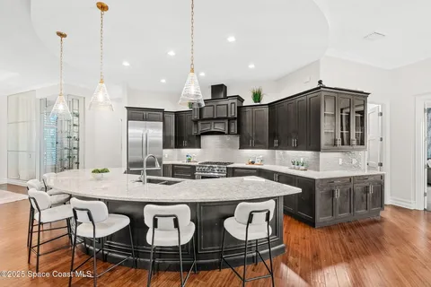 a living room with stainless steel appliances kitchen island granite countertop a sink a stove and a wooden floors