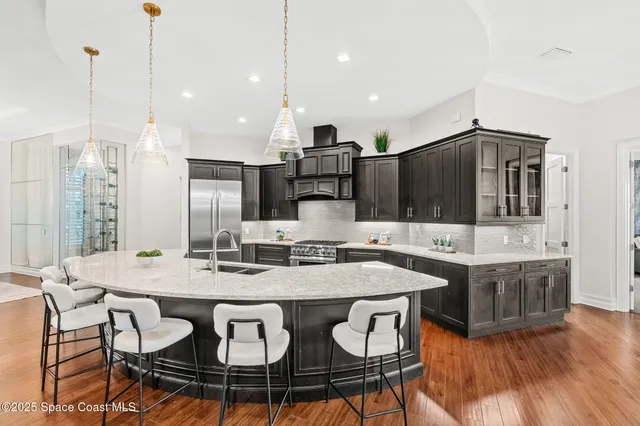a living room with stainless steel appliances kitchen island granite countertop a sink a stove and a wooden floors