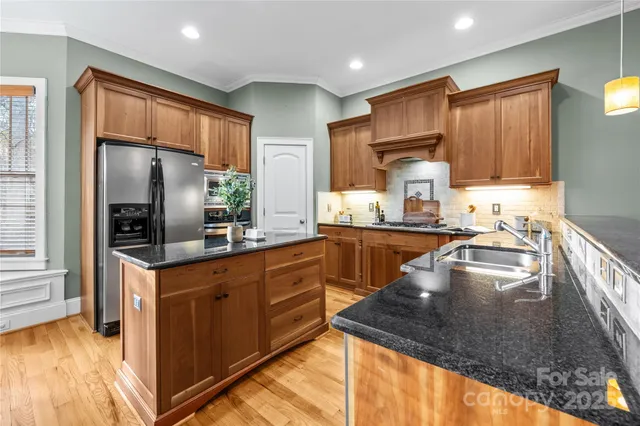 a kitchen with stainless steel appliances granite countertop a sink a stove and a refrigerator
