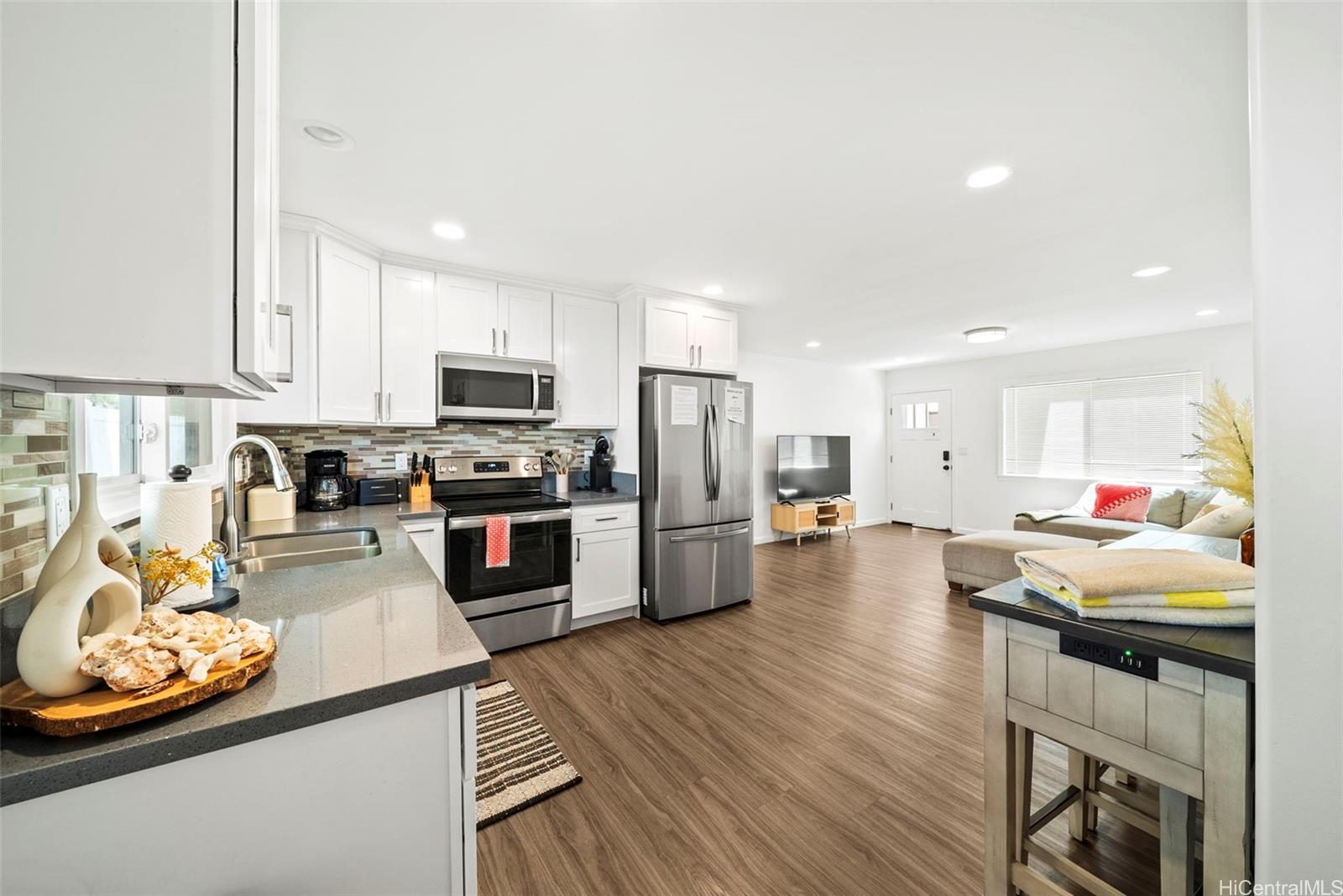 87-1446 Akowai Road Waianae, HI 96792 - Photo 17 of 23 a kitchen with stainless steel appliances granite countertop a refrigerator oven a stove top oven a sink dishwasher and white cabinets with wooden floor