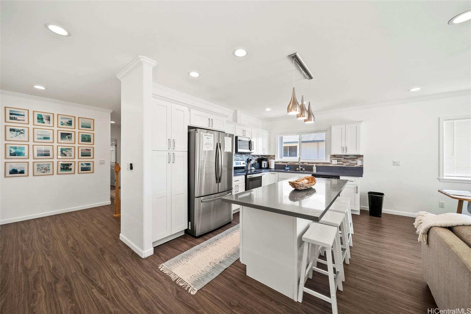 87-1446 Akowai Road Waianae, HI 96792 - Photo 8 of 23 a kitchen with stainless steel appliances kitchen island granite countertop a refrigerator a stove a sink dishwasher and a dining table with wooden floor