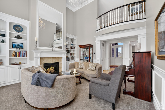 714 Draper Heights Way Draper, UT 84020 - Photo 24 of 88 Carpeted living room featuring built in shelves, a high ceiling, a wainscoted wall, crown molding, and a decorative wall