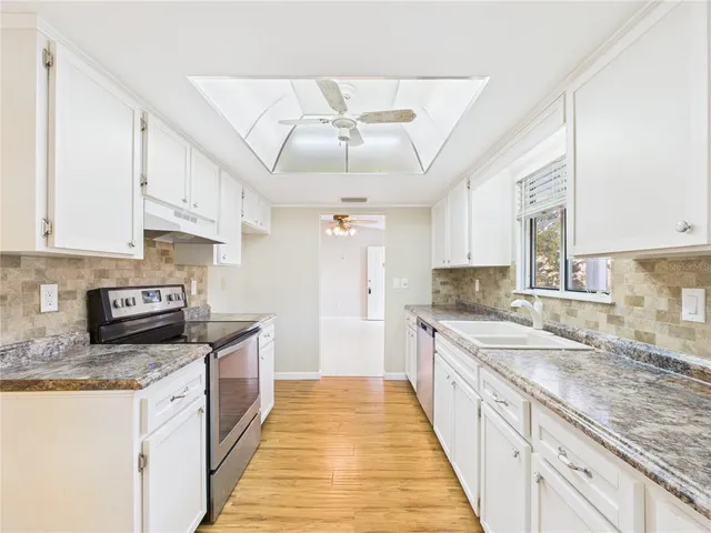 a large kitchen with stainless steel appliances granite countertop a sink stove and refrigerator