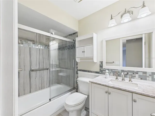 a bathroom with a shower sink vanity mirror and toilet