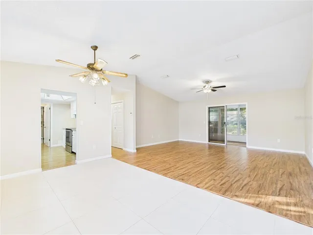 a view of a livingroom with a chandelier fan and wooden floor