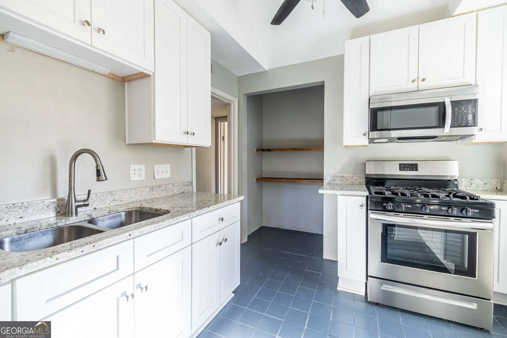 1570 Spring Lane Northwest, Unit B Atlanta, GA 30314 - Photo 11 of 26 a kitchen with white cabinets stainless steel appliances and sink