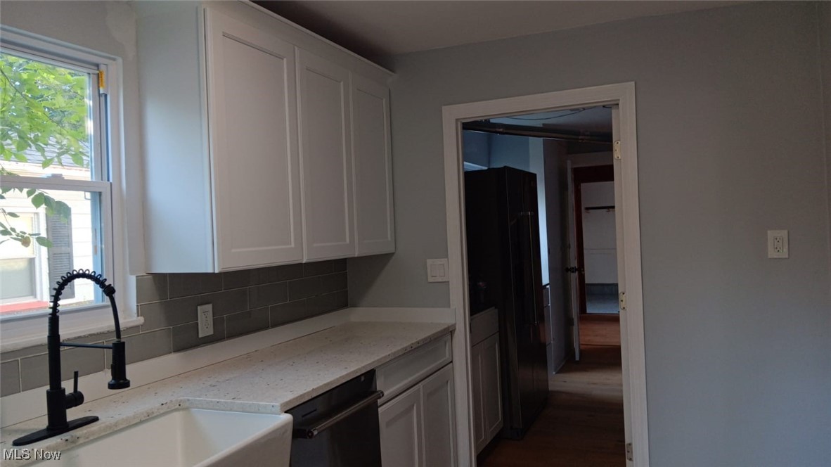 3999 Lancaster Road South Euclid, OH 44121 - Photo 14 of 17 Kitchen featuring white cabinets, sink, tasteful backsplash, dishwasher, and light stone countertops