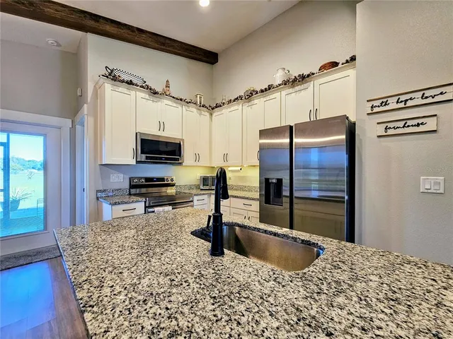 a kitchen with stainless steel appliances granite countertop a sink and a refrigerator