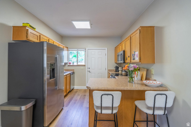 700 North Main Street, Unit F3 Washington, UT 84780 - Photo 7 of 34 Kitchen featuring wood-finish cabinetry, stainless steel appliances, and a breakfast bar with a laminate countertop