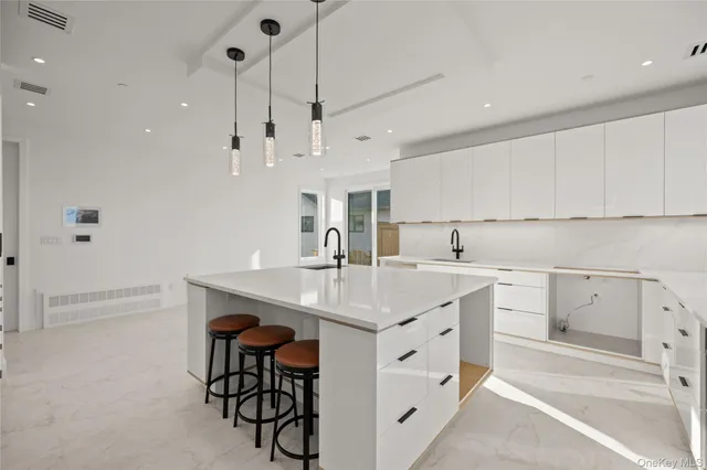 a large white kitchen with granite countertop a large window and white stainless steel appliances