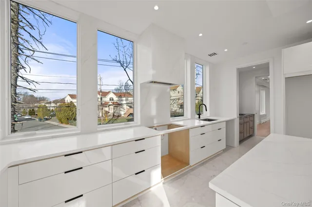a large white kitchen with stainless steel appliances granite countertop a sink and cabinets with wooden floor