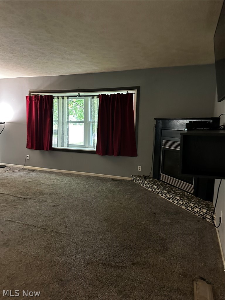 198 Park Road Painesville, OH 44077 - Photo 6 of 31 Living area featuring a window with white trim, dark gray walls, and a built-in fireplace with a mosaic tile hearth