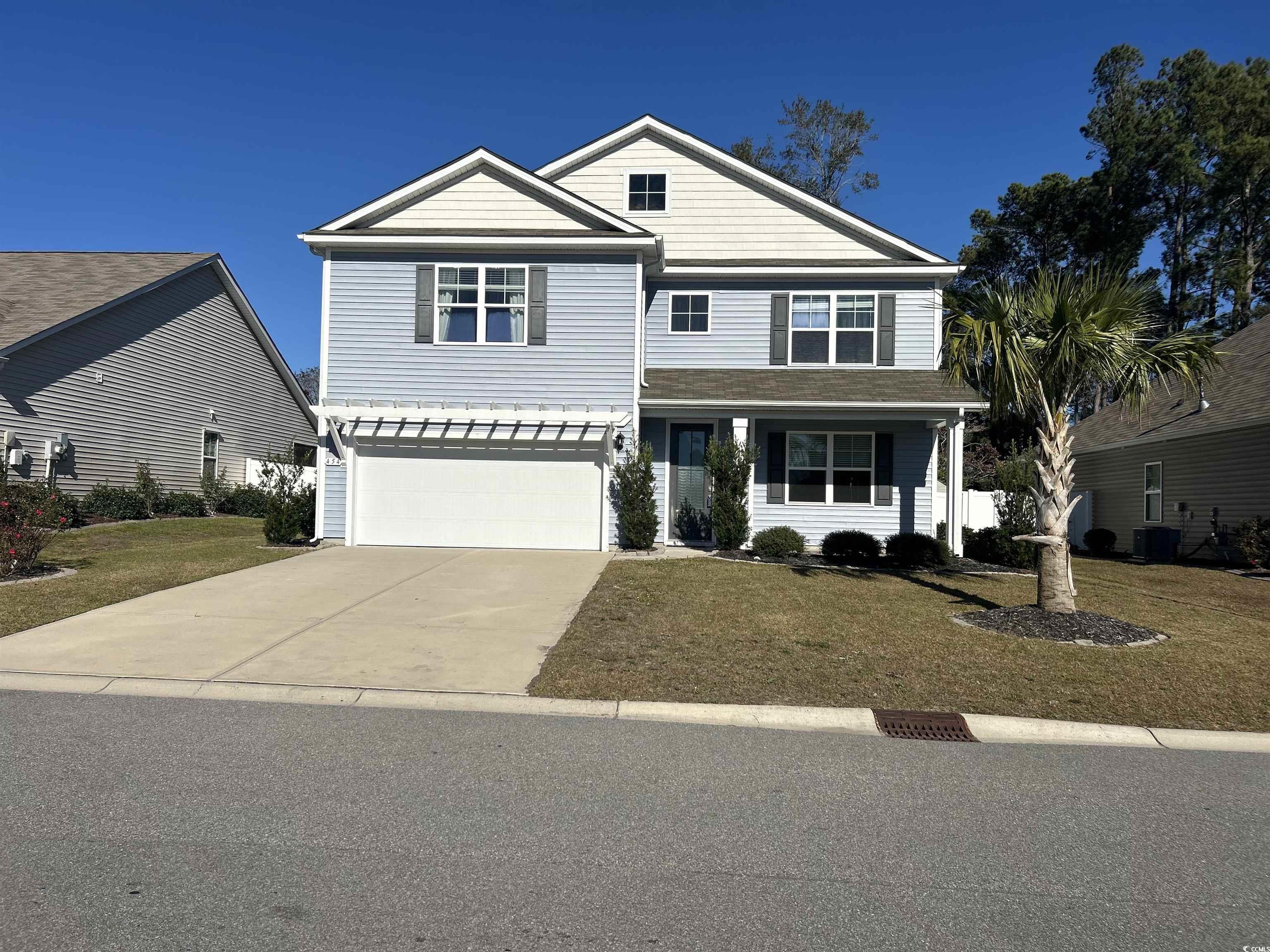 View of front of home featuring concrete driveway, a front yard, covered porch, and a garage
