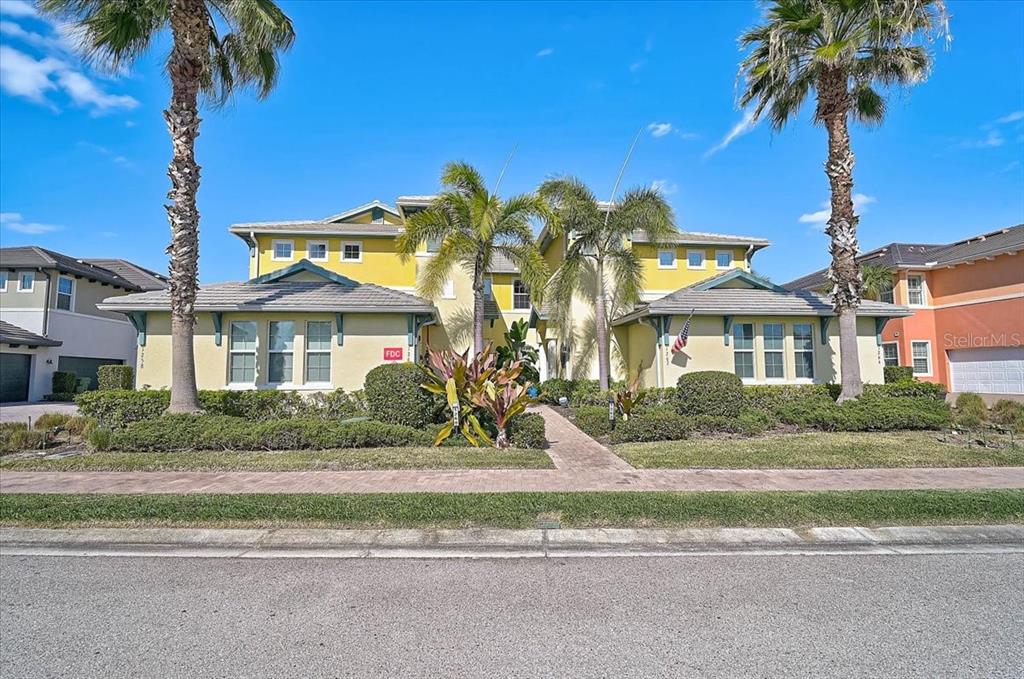 a front view of a multi story residential apartment building with yard and palm tree