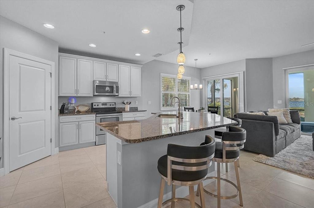 1258 Riverscape Street, Unit A Bradenton, FL 34208 - Photo 16 of 63 a large kitchen with kitchen island granite countertop lots of white cabinets appliances and furniture