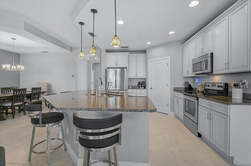 1258 Riverscape Street, Unit A Bradenton, FL 34208 - Photo 7 of 63 a kitchen with stainless steel appliances granite countertop a stove a sink a refrigerator a stove a dining table and chairs