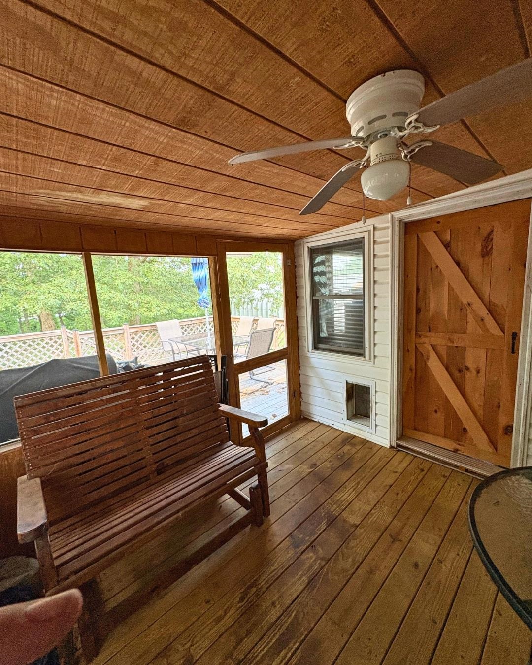 772 Rushing Road Michie, TN 38357 - Photo 8 of 19 Screened porch featuring a wood-finish plank ceiling and flooring, a ceiling fan with integrated lighting, and a barn-style wood door