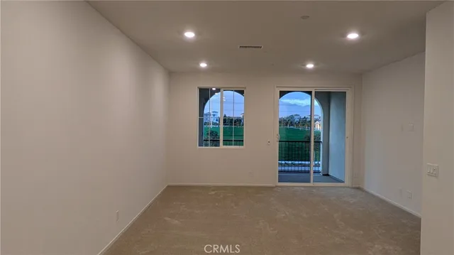 an empty room with windows and ceiling fan