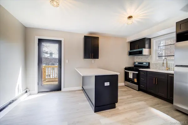 a view of an empty room with a kitchen and a window