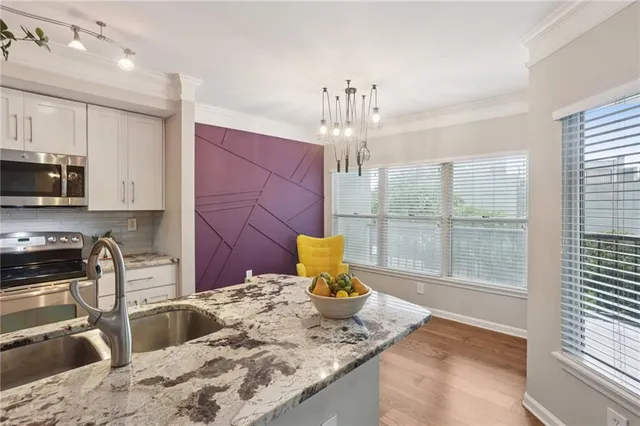 a kitchen with stainless steel appliances granite countertop a sink a stove and a wooden cabinets