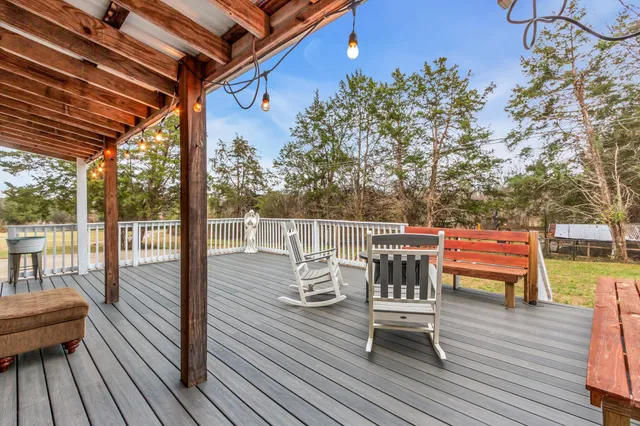 a view of a roof deck with table and chairs a barbeque with wooden floor and fence