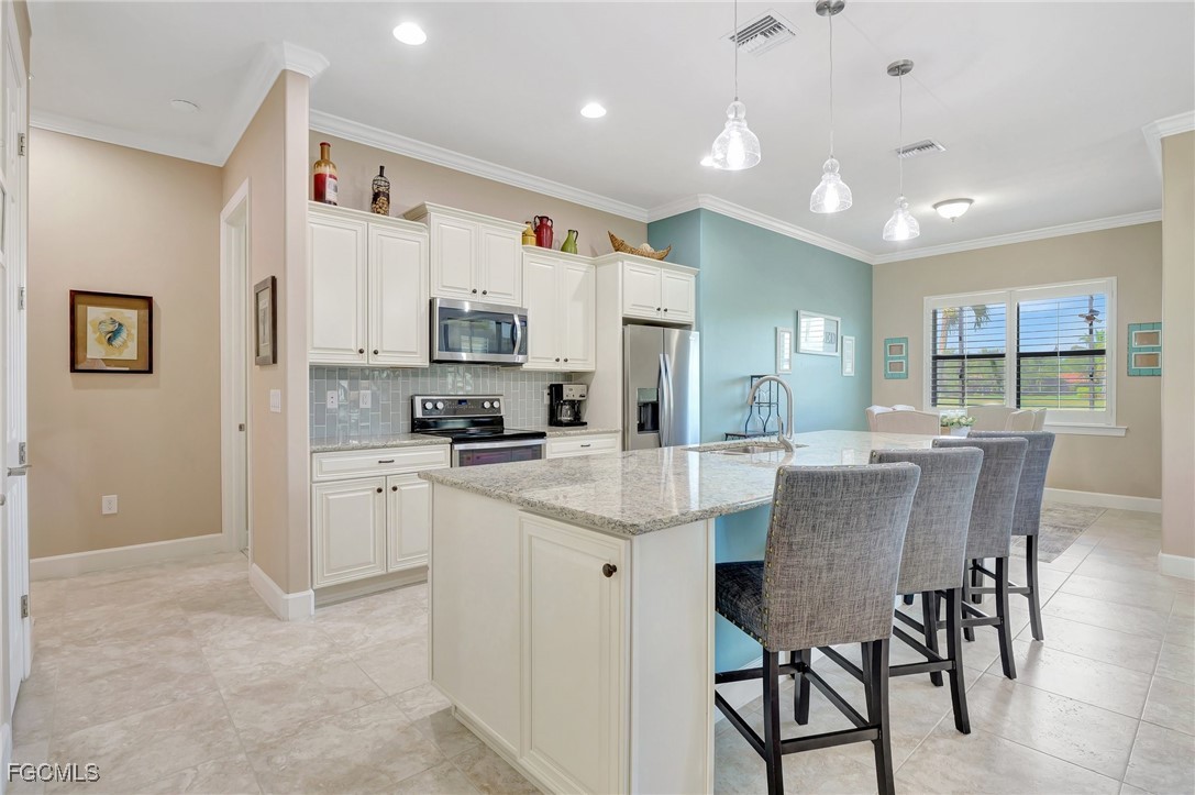 11716 Avingston Terrace Fort Myers, FL 33913 - Photo 8 of 49 a kitchen with kitchen island a stove a table and chairs