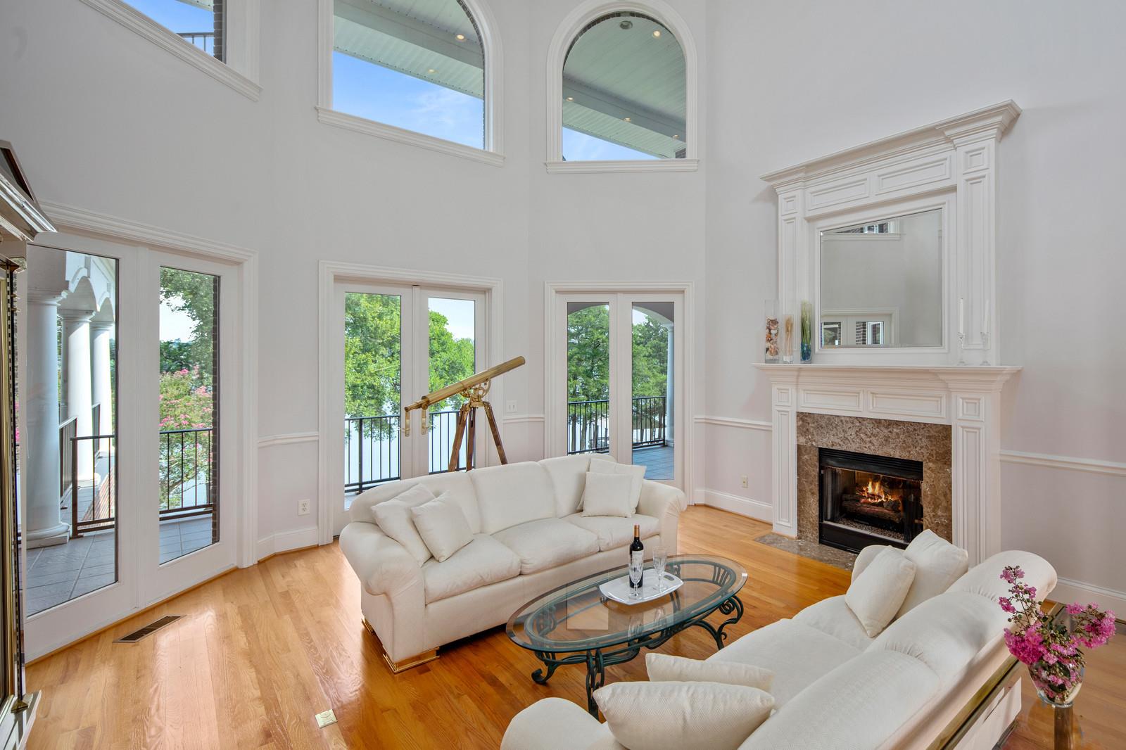 This grand living room has soaring 20ft ceilings with gorgeous lake views. The gas log fireplace is surrounded with granite and a traditional mantle