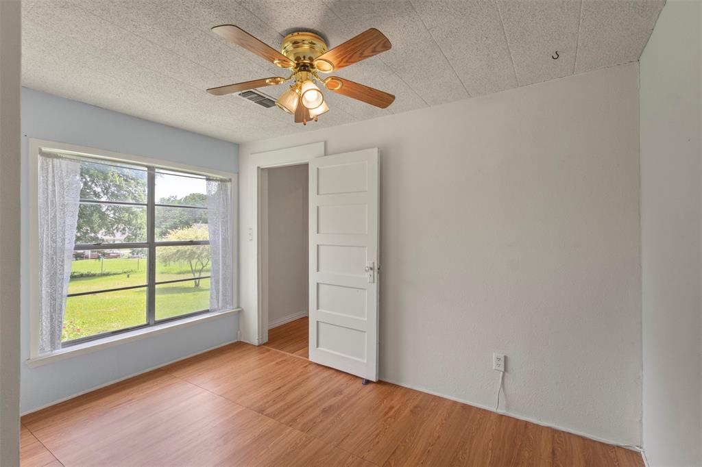 829 West 9th Street Bonham, TX 75418 - Photo 21 of 30 Bright interior room featuring wood-finish flooring, a ceiling fan with light fixture, and a large window overlooking a grassy exterior