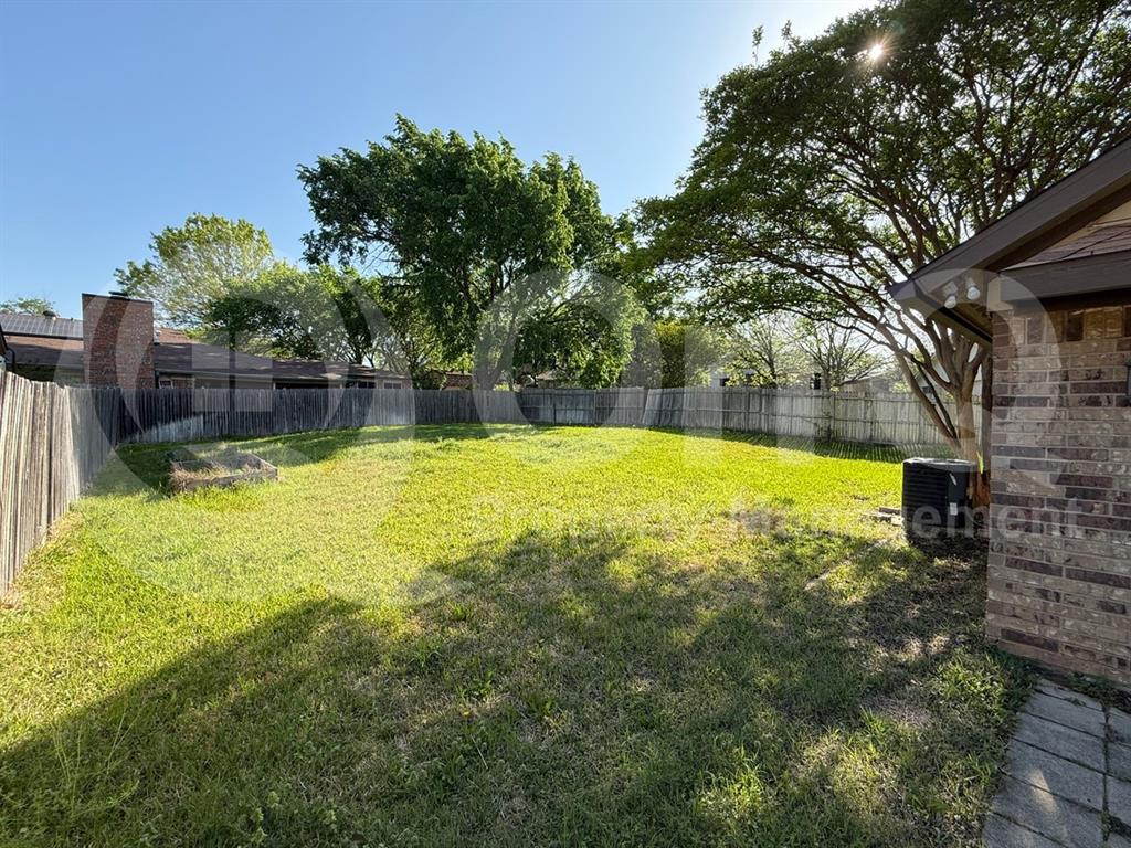 3005 Meandering Way Bedford, TX 76021 - Photo 21 of 24 Expansive backyard featuring a lush lawn, mature trees, wood privacy fencing, and a brick exterior with a paved pathway