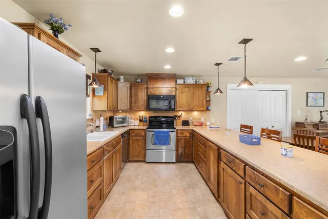 a kitchen with stainless steel appliances granite countertop a sink refrigerator and cabinets