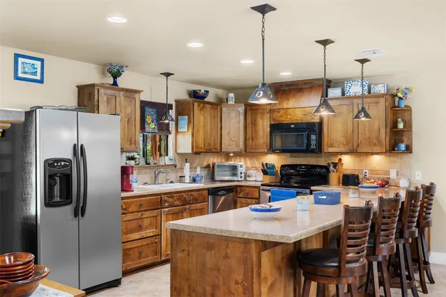a kitchen with stainless steel appliances a table chairs refrigerator and microwave