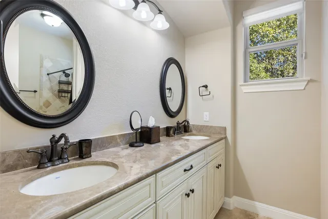 a bathroom with a granite countertop double vanity sink and a mirror