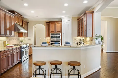 a kitchen with stainless steel appliances granite countertop a stove a sink dishwasher and cabinets with wooden floor