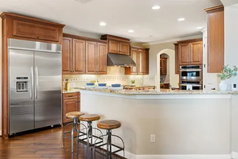 a kitchen with stainless steel appliances granite countertop a refrigerator and a stove top oven