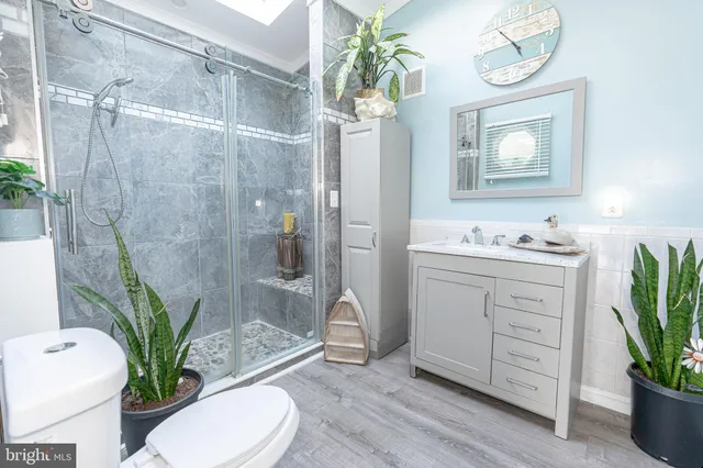 a bathroom with a granite countertop sink a toilet a potted plant and a shower