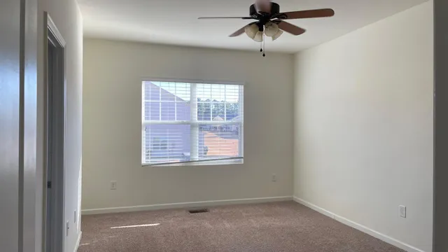 an empty room with a window and a fan