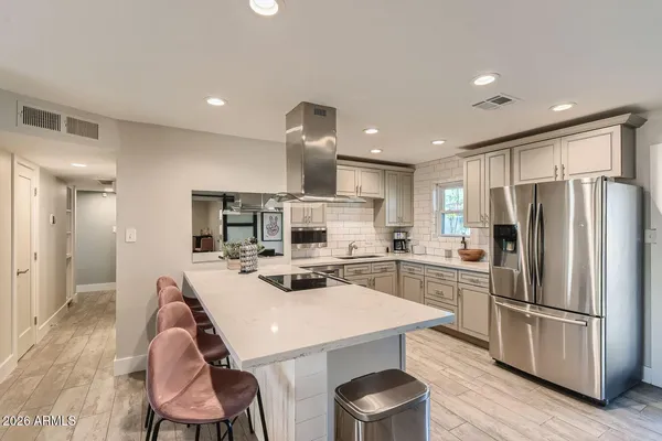 a kitchen with a dining table chairs refrigerator and microwave