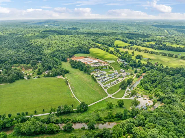 an aerial view of a residential houses with outdoor space and trees all around