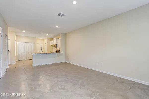 a view of an empty room and a kitchen
