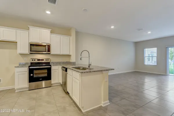 a kitchen with stainless steel appliances granite countertop a stove a sink and a microwave